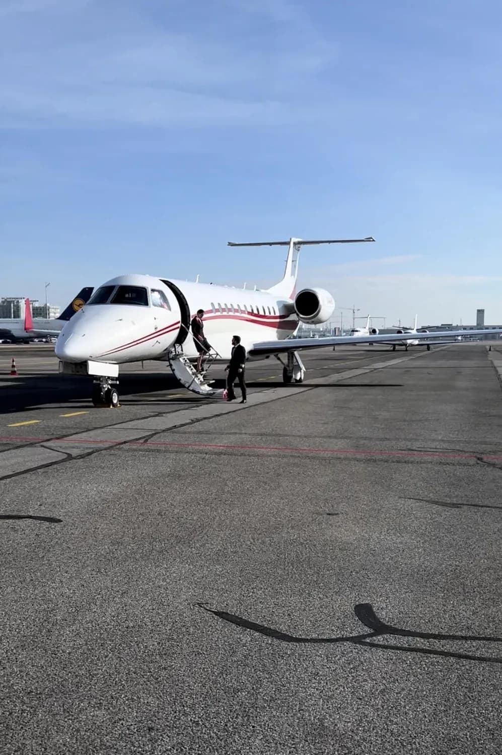 Privatjet auf dem Rollfeld, zwei Personen gehen über die ausgeklappte Treppe an Bord